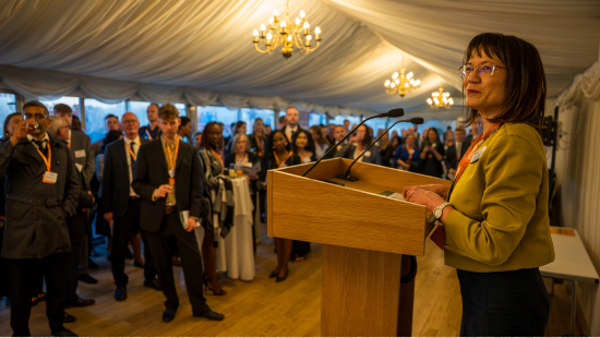 Dr Louise Leong FRSB giving a speech at a podium in front of a crowd of graduates