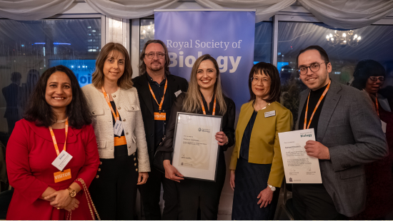 Award winners holding their certificates and standing in front of RSB banner with Dr Lousie Leong FRSB