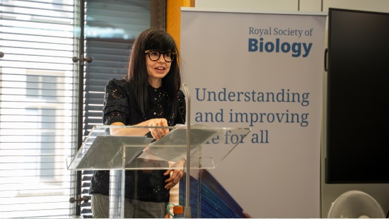 Dr Jess Wade giving speech at lectern in front of RSB banner